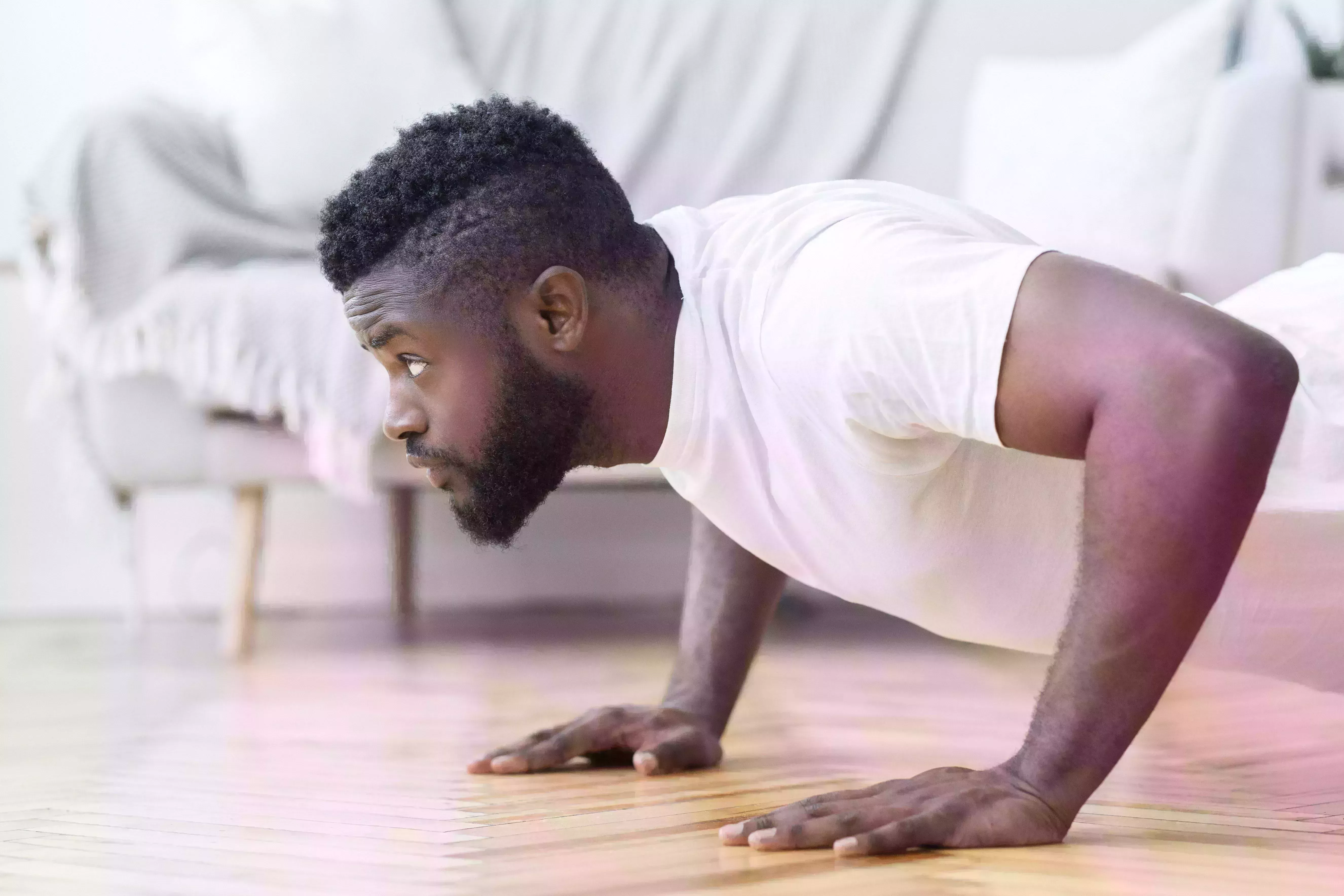 young black man exercising in his house gym, doing push ups, side view, free space