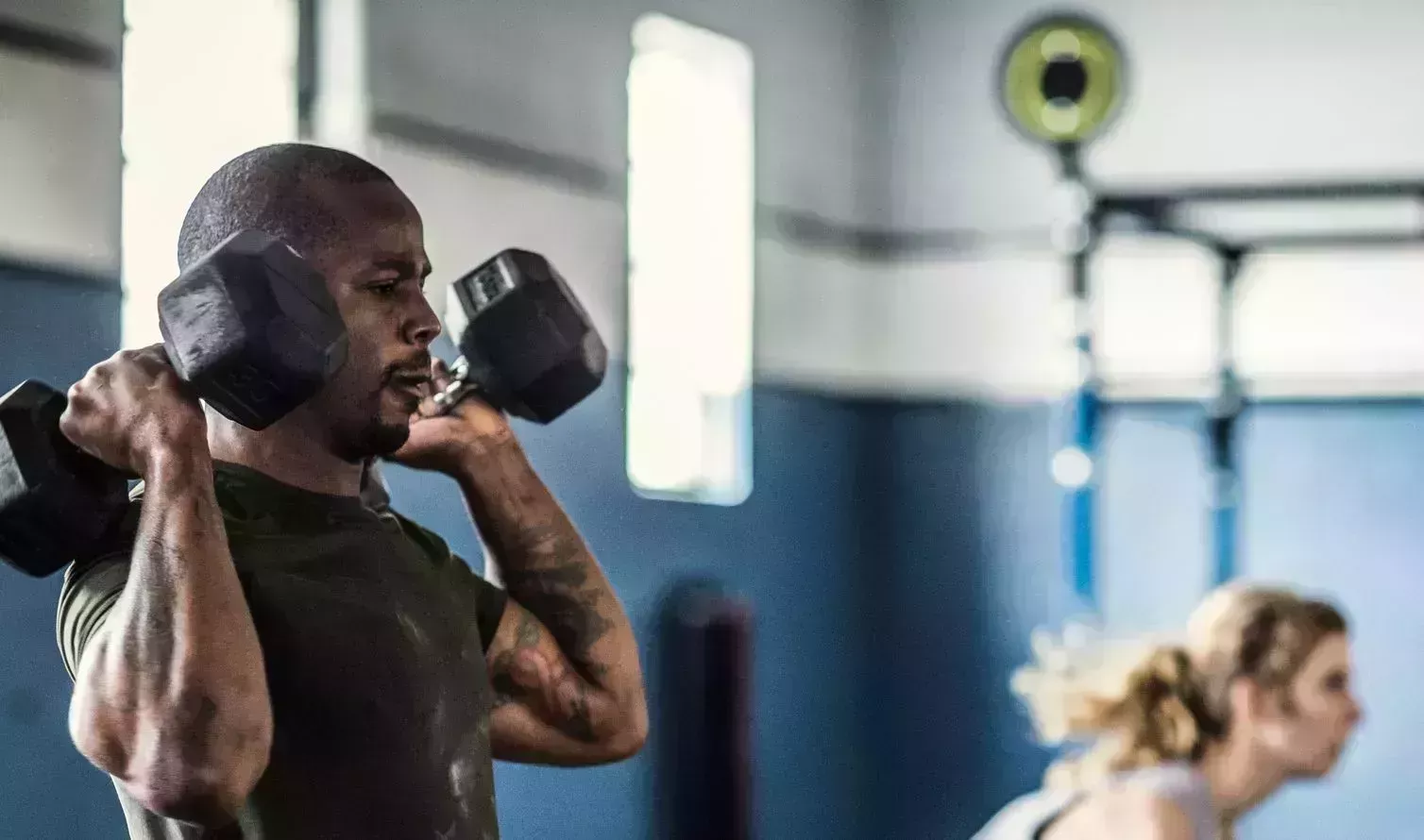 man lifting dumbells at cross training gym