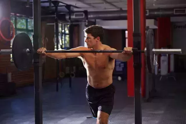 bare chested man in gym preparing to lift weights