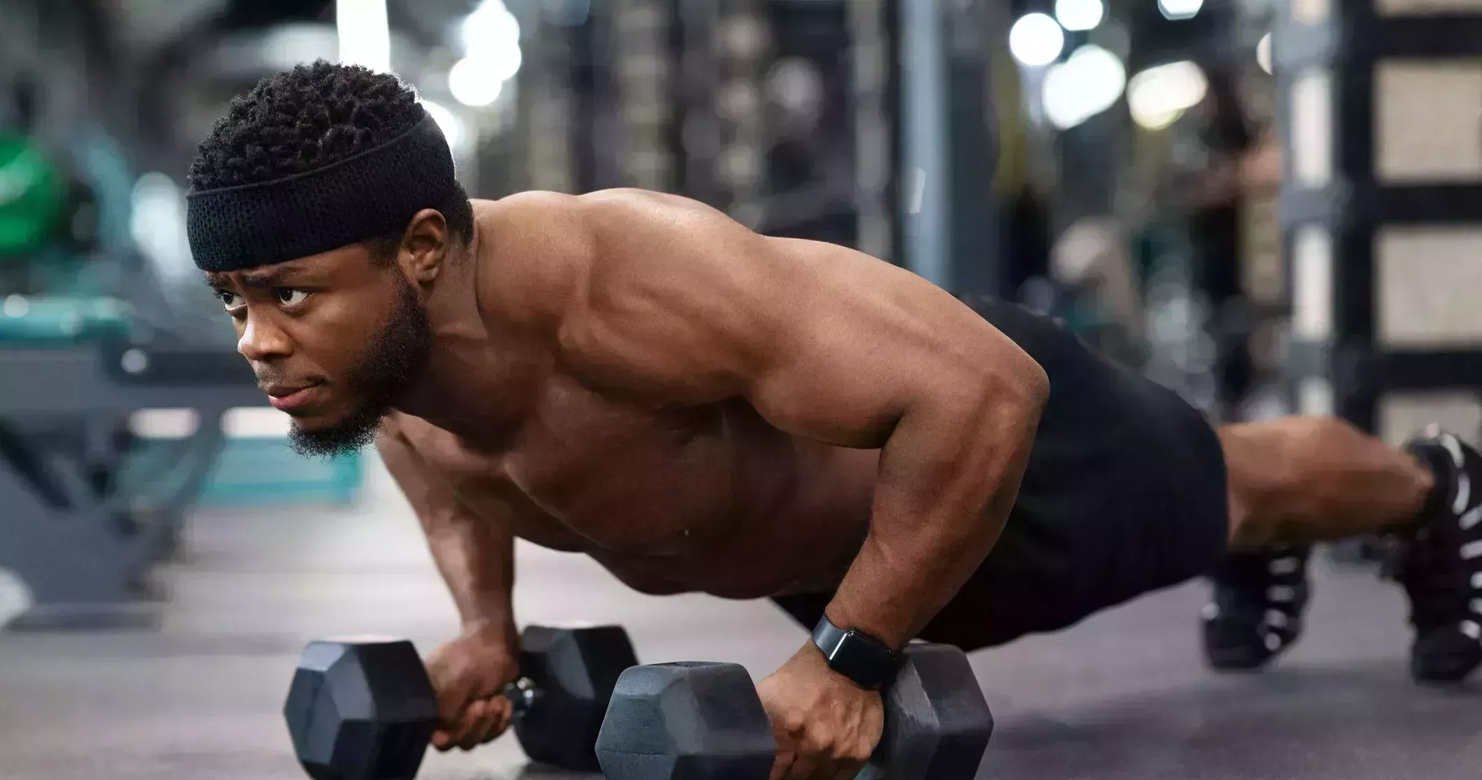concentrated black guy sportsman pushing up with dumbbells