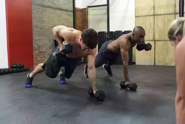 athletes doing push ups with dumbbells at gym