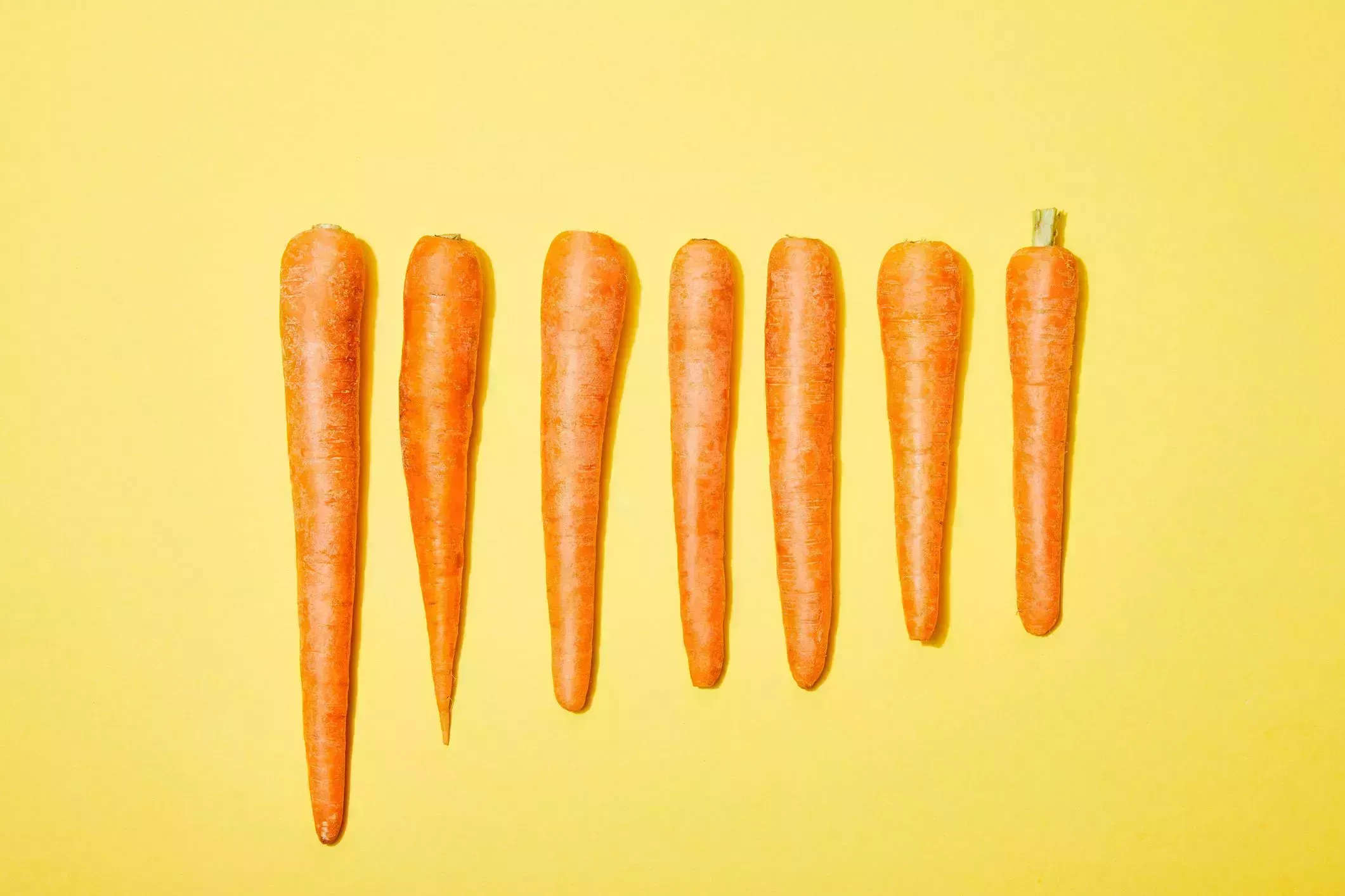 top view of carrots in row on yellow background