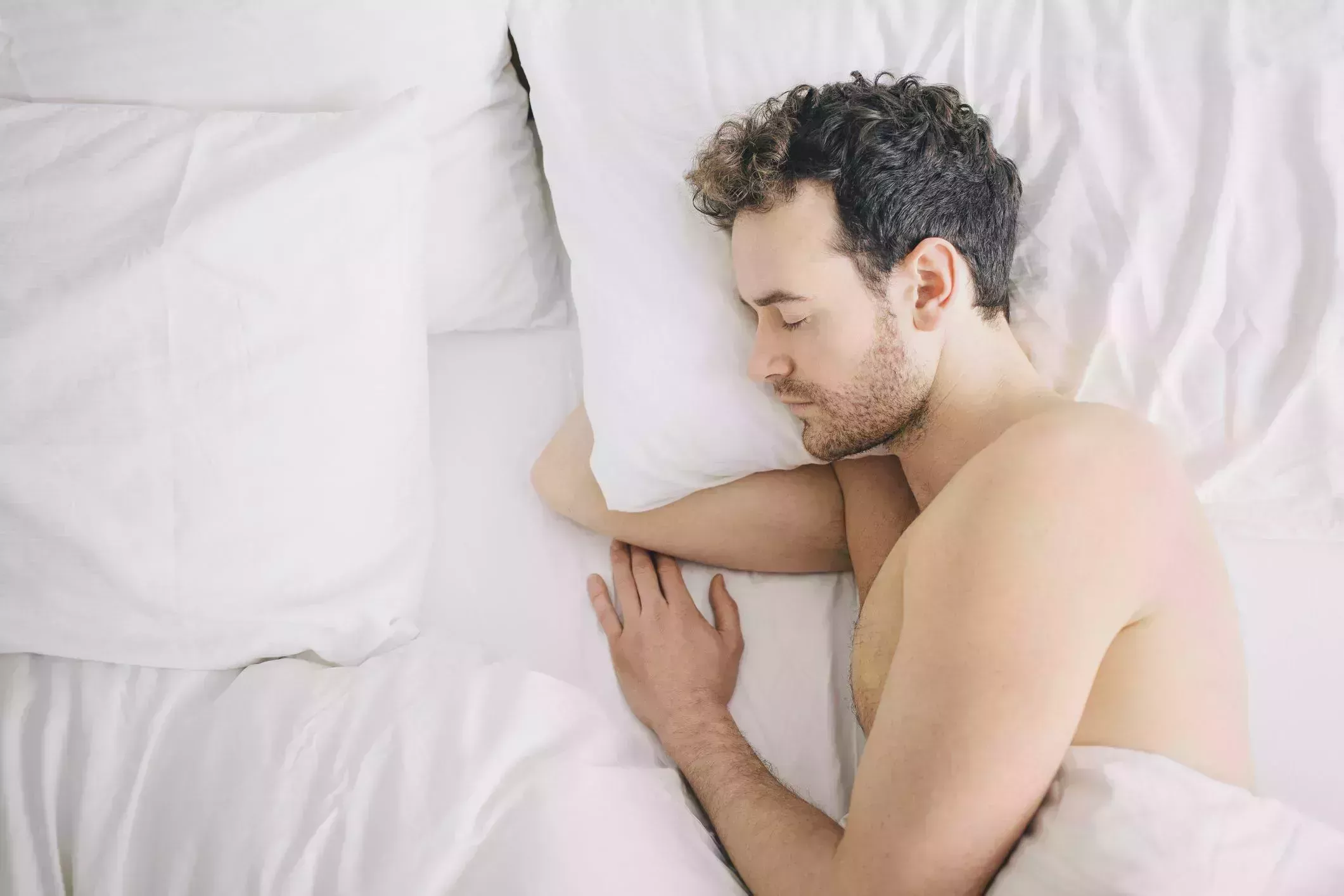 overhead view of young man lying asleep in bed