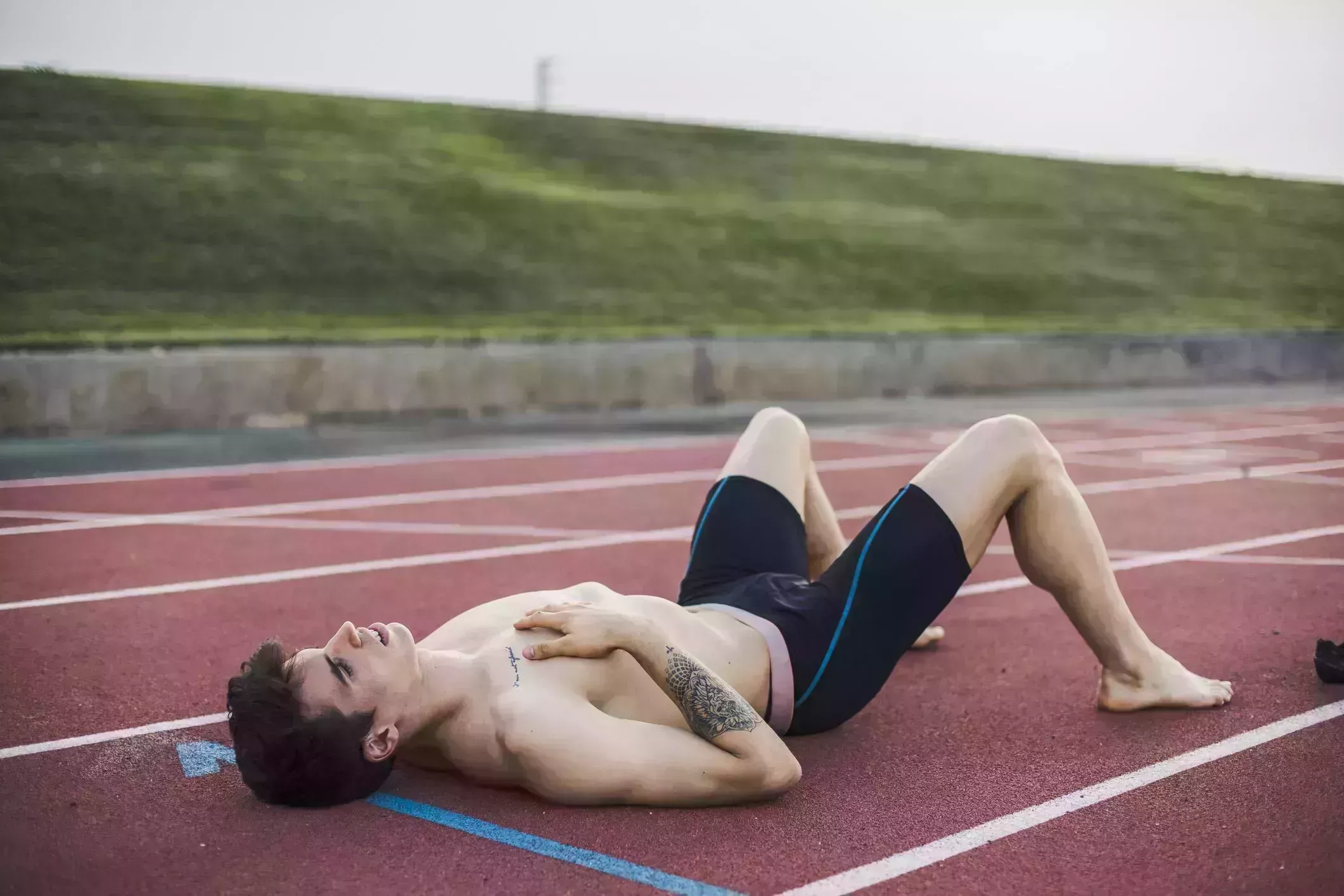 athlete lying resting on a tartan track after finishing a race