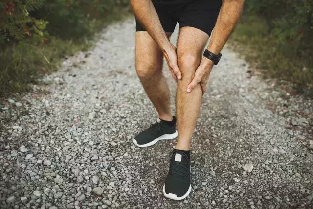 knee injury on running outdoors man holding knee by hands close up and suffering with pain sprain ligament or meniscus problem