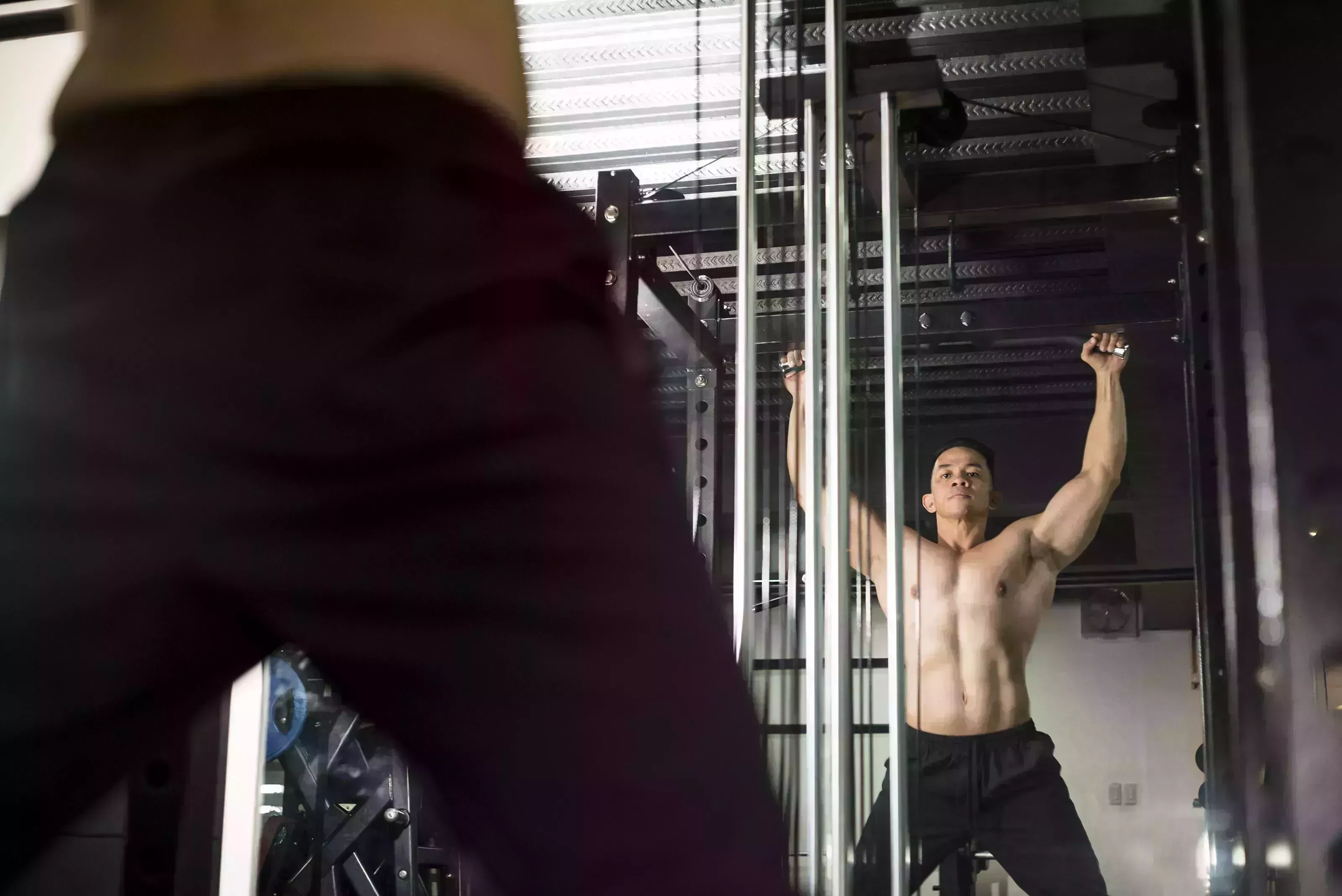 a fit and athletic 40 year old asian male prepares to do pullups working out and training scene at the gym or fitness center