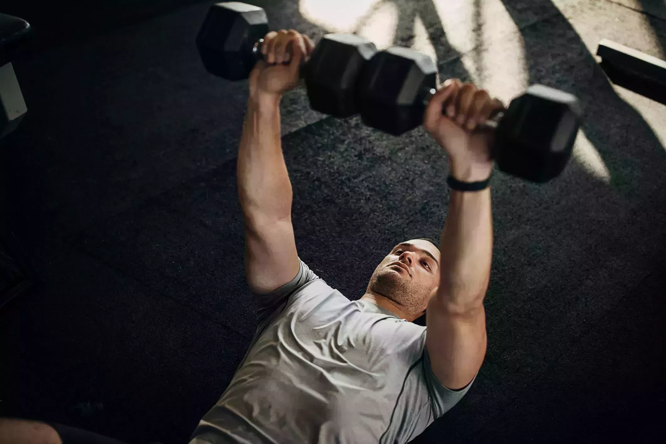 man training with dumbbells on the floor in gym