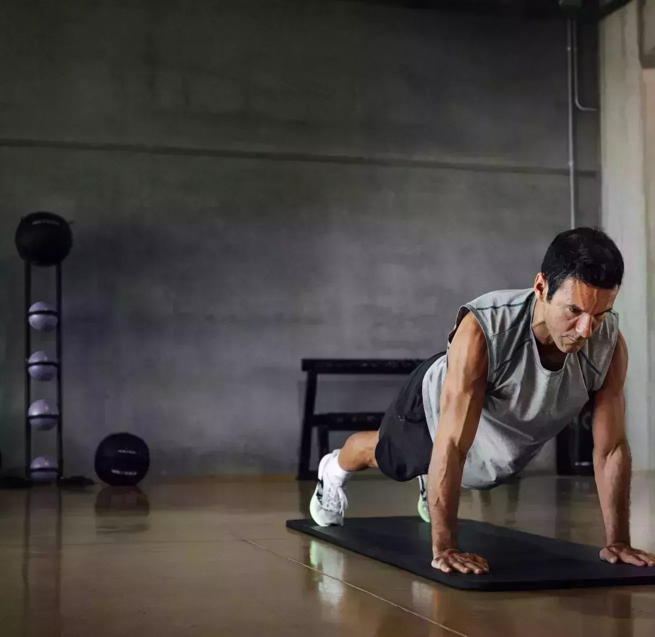 athletic man doing pushups exercise at dark gym