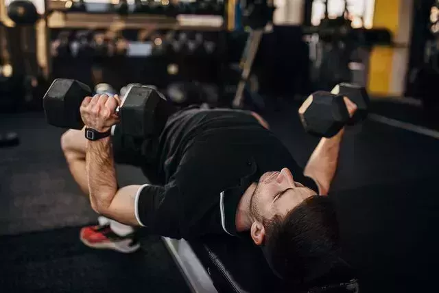 muscular man exercising on weight with dumbbells
