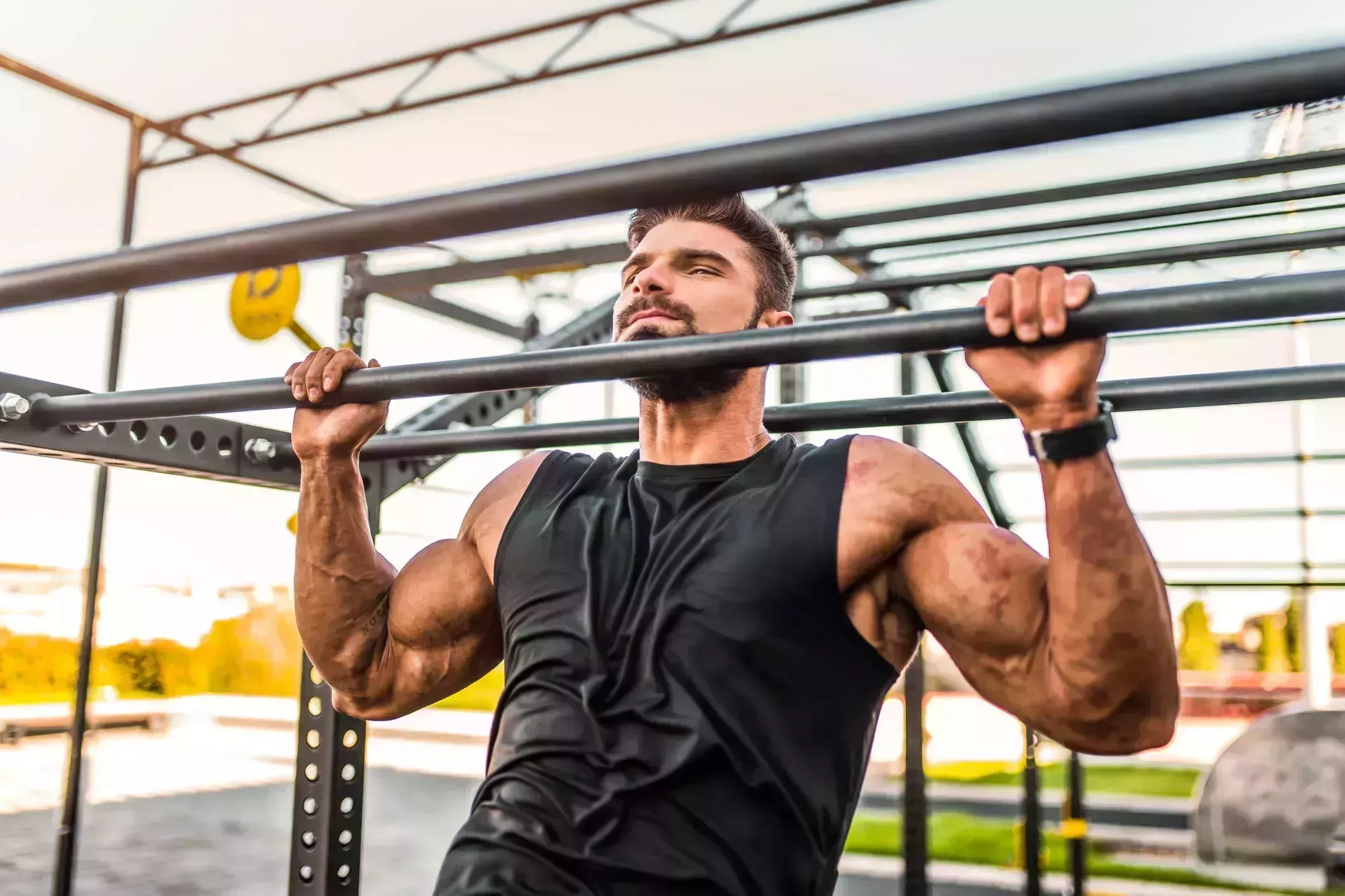 young bodybuilder doing pullups at the outdoor gym