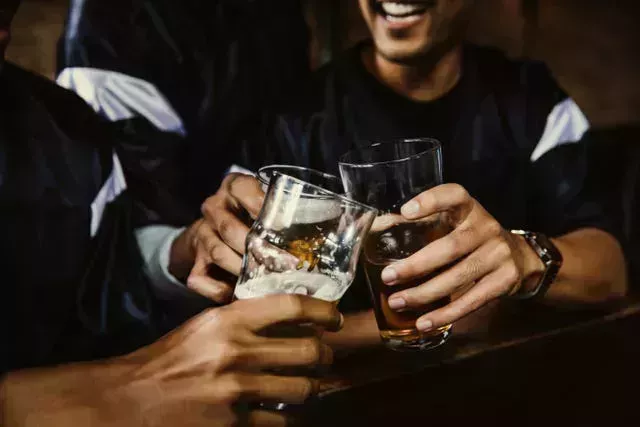 male football fans toasting beer glasses in bar