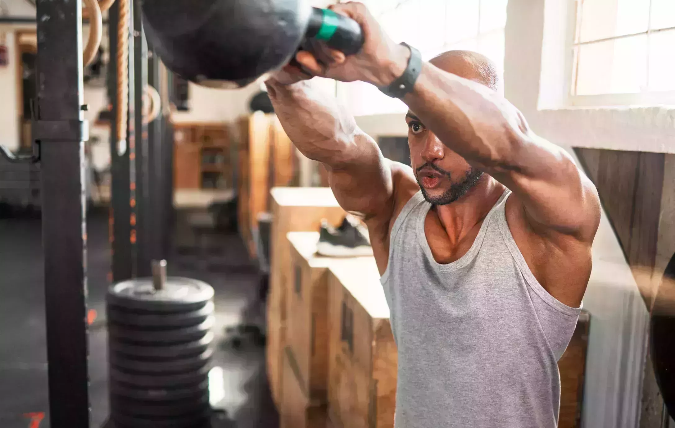 shot of a young man doing kettlebell swings during his workout