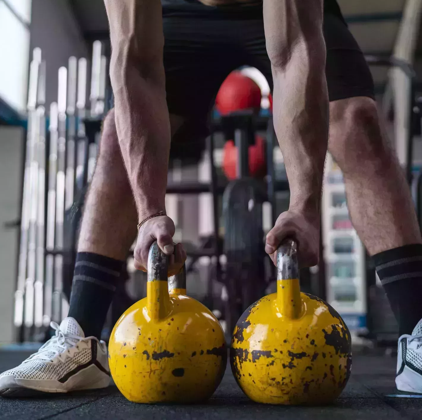 muscular male athlete holding kettlebells in gym