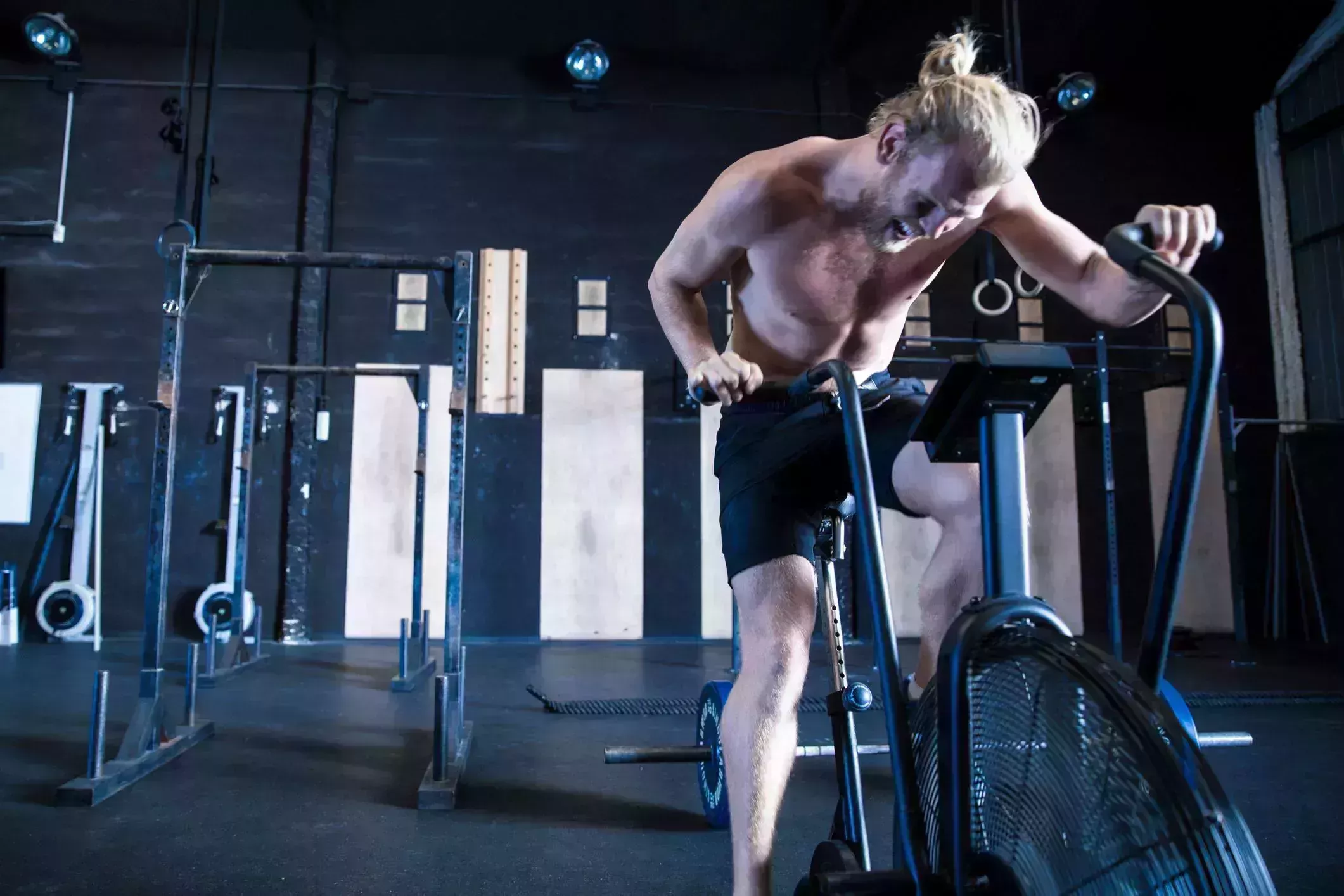 man exercising in gymnasium, using air resistance exercise bike