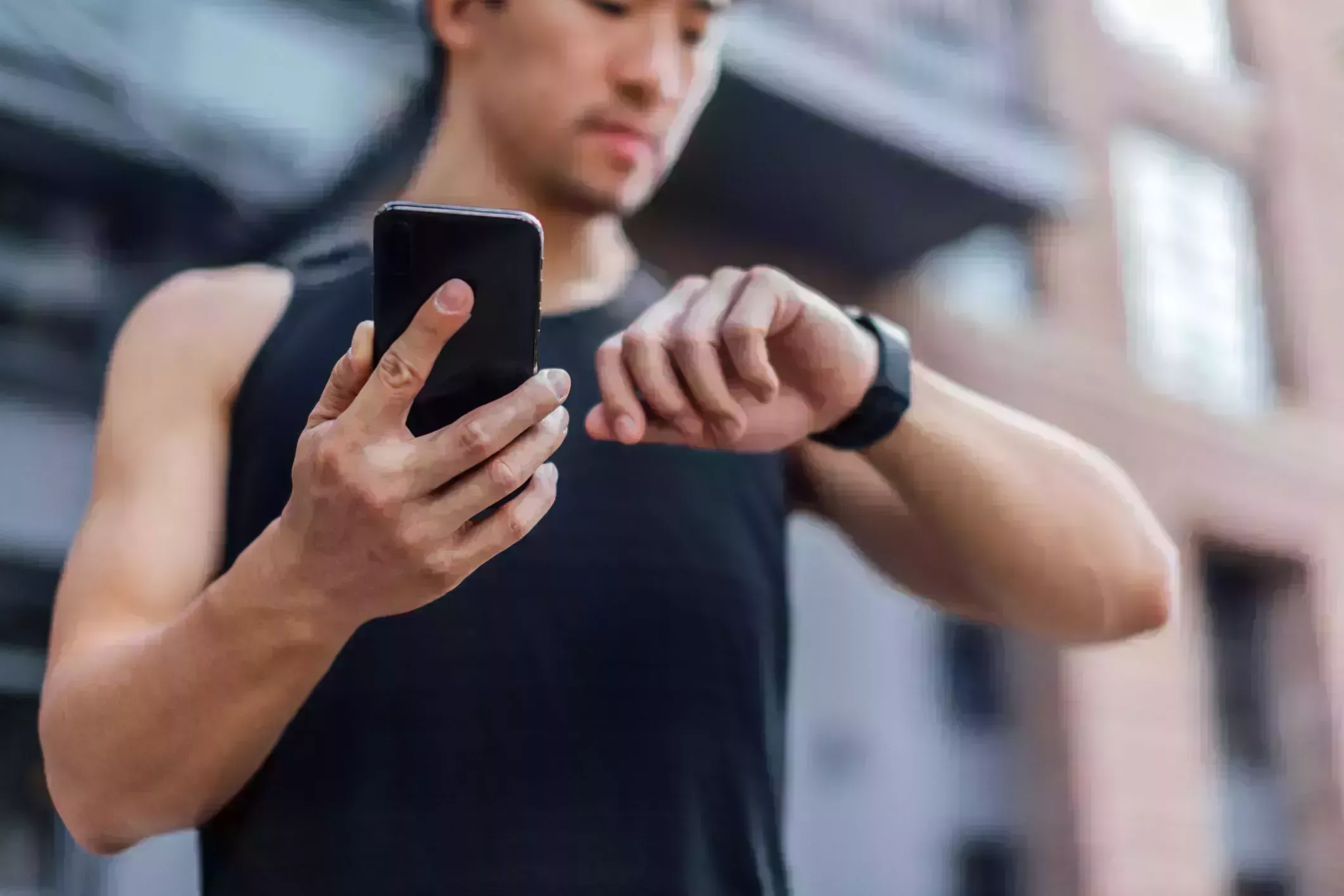 young man using fitness app on smart phone and smart watch for tracking workout