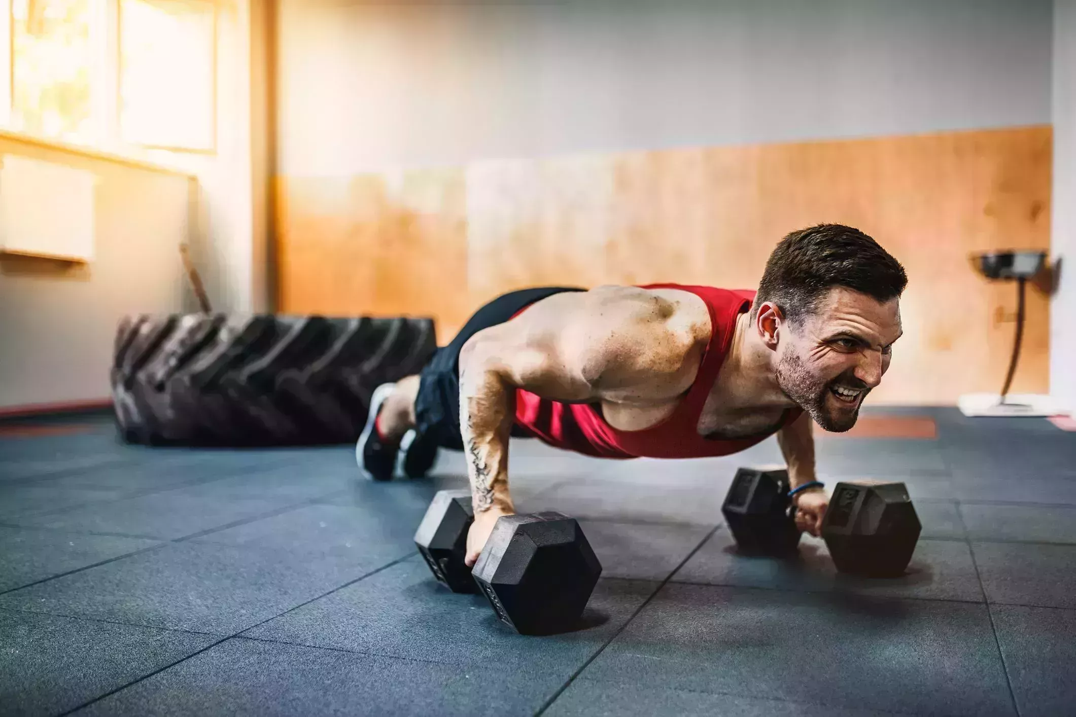 muscular man doing pushup exercise with dumbbell