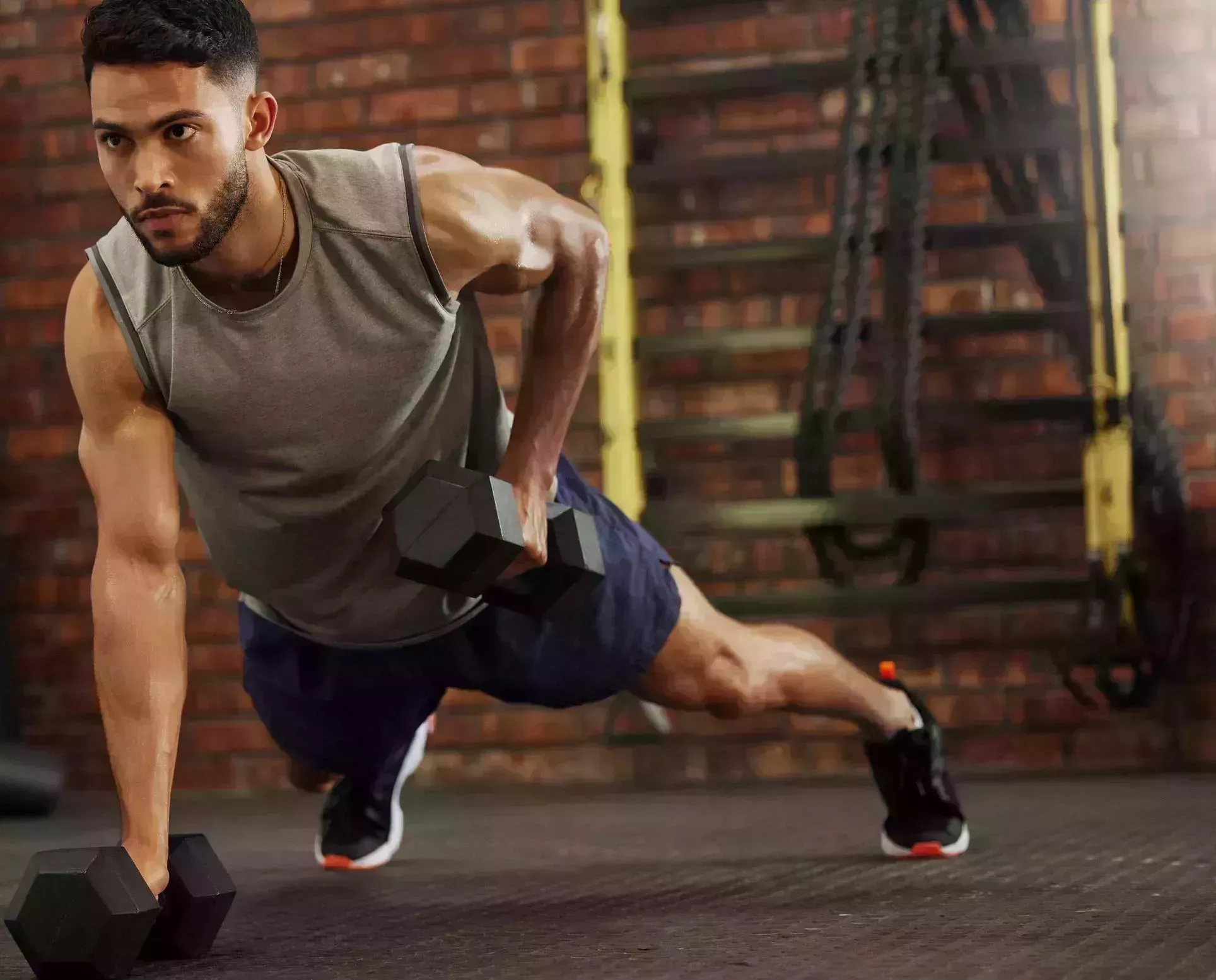 shot of a young man working out with dumbbells in a gym