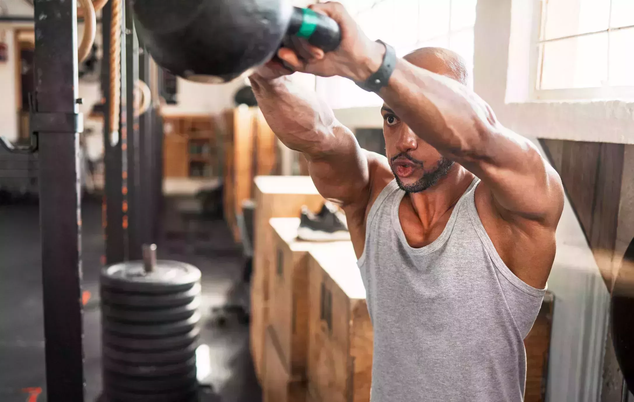 Shot of a young man doing kettlebell swings during his workout