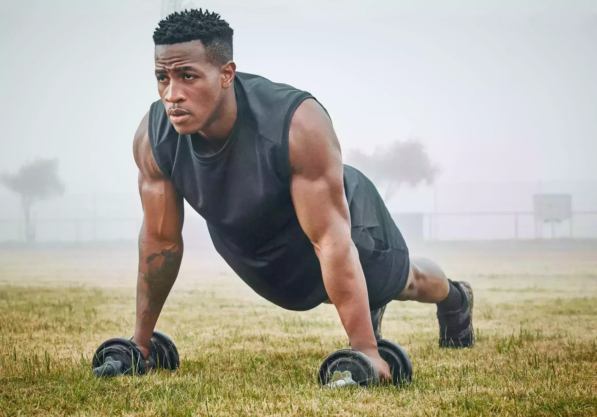 shot of a muscular young man exercising with dumbbells outdoors