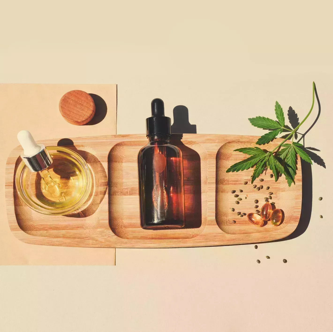 cbd oil, tincture with marijuana leaves on a beige background cannabis seeds in a wooden spoon medical cannabis concept for health and cosmetics minimalism