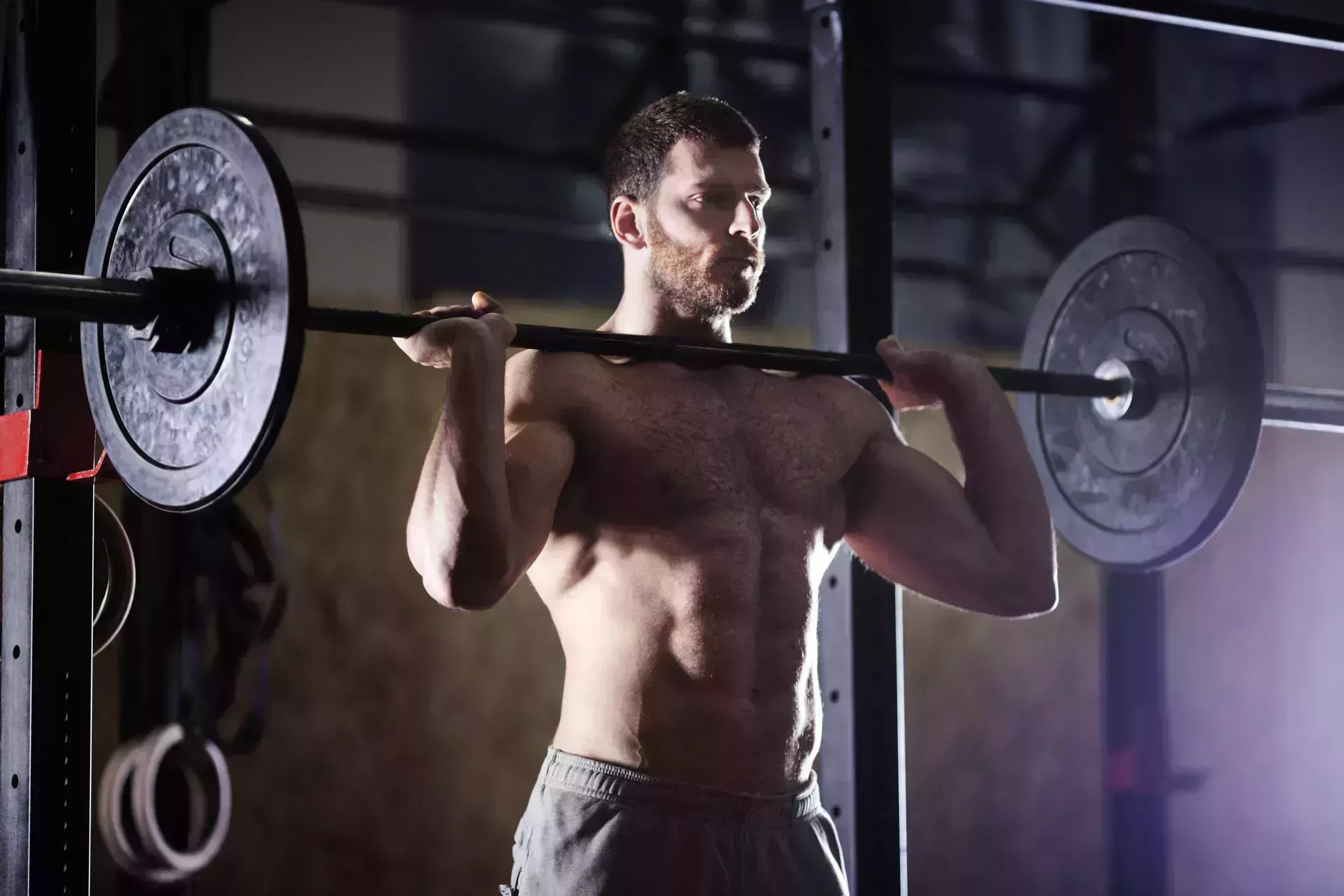 confident man lifting barbells in gym