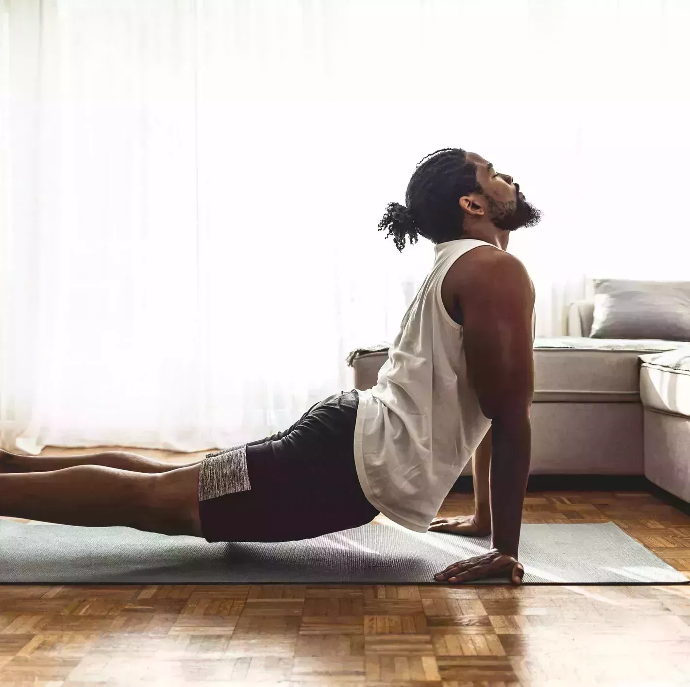 indoor shot of handsome young man practicing yoga fitness man meditating with his eyes closed while doing cobra pose in living room