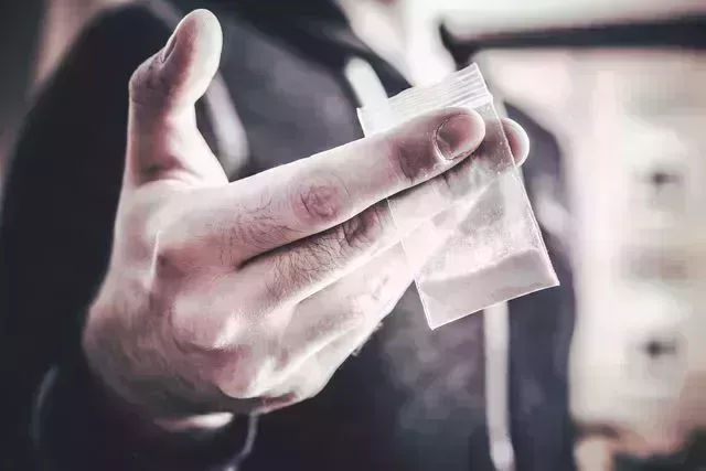 dealing drugs by a man holding one little bag with white powder in his hand