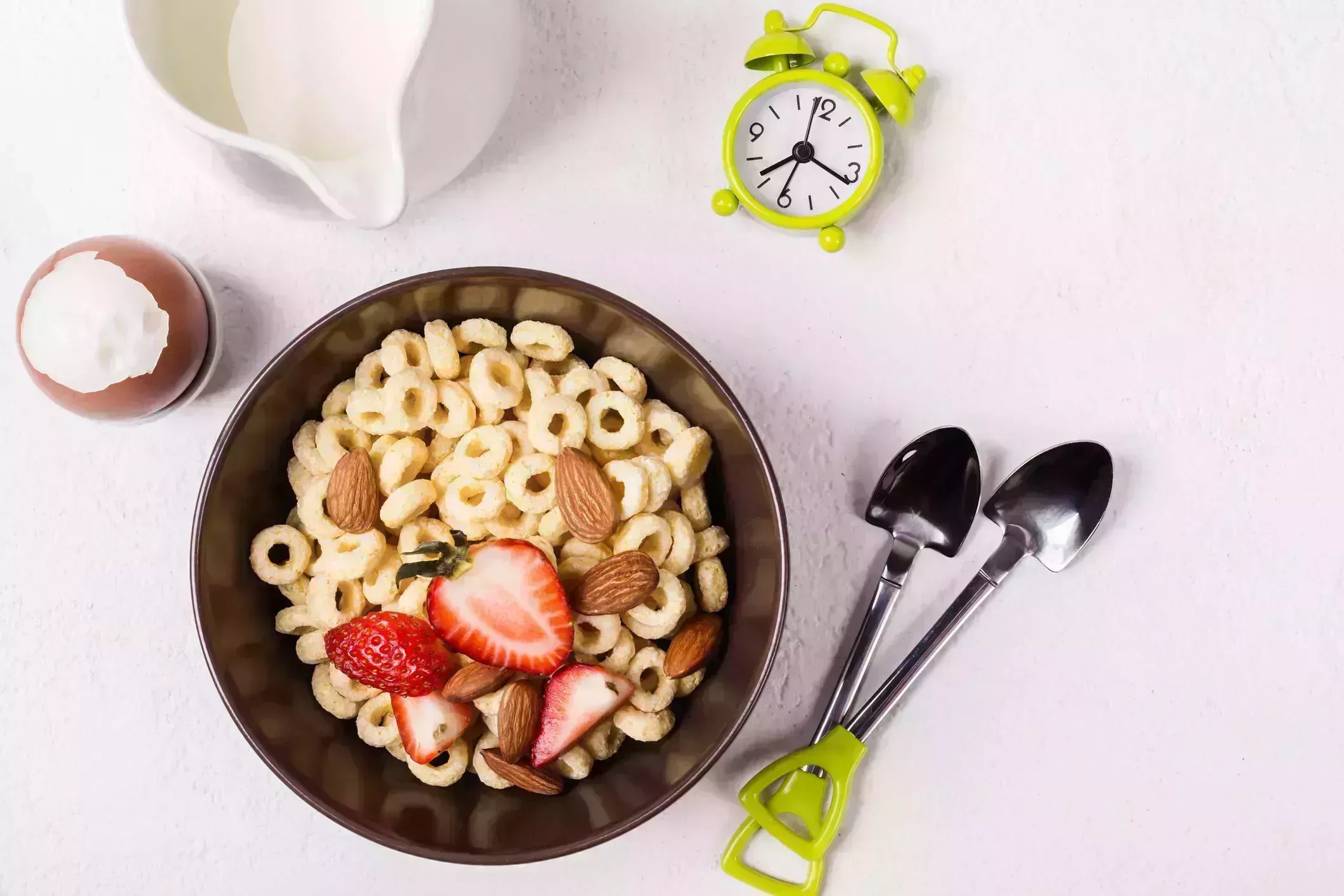 balanced traditional breakfast whole grain rings cheerios, berries and egg on white table