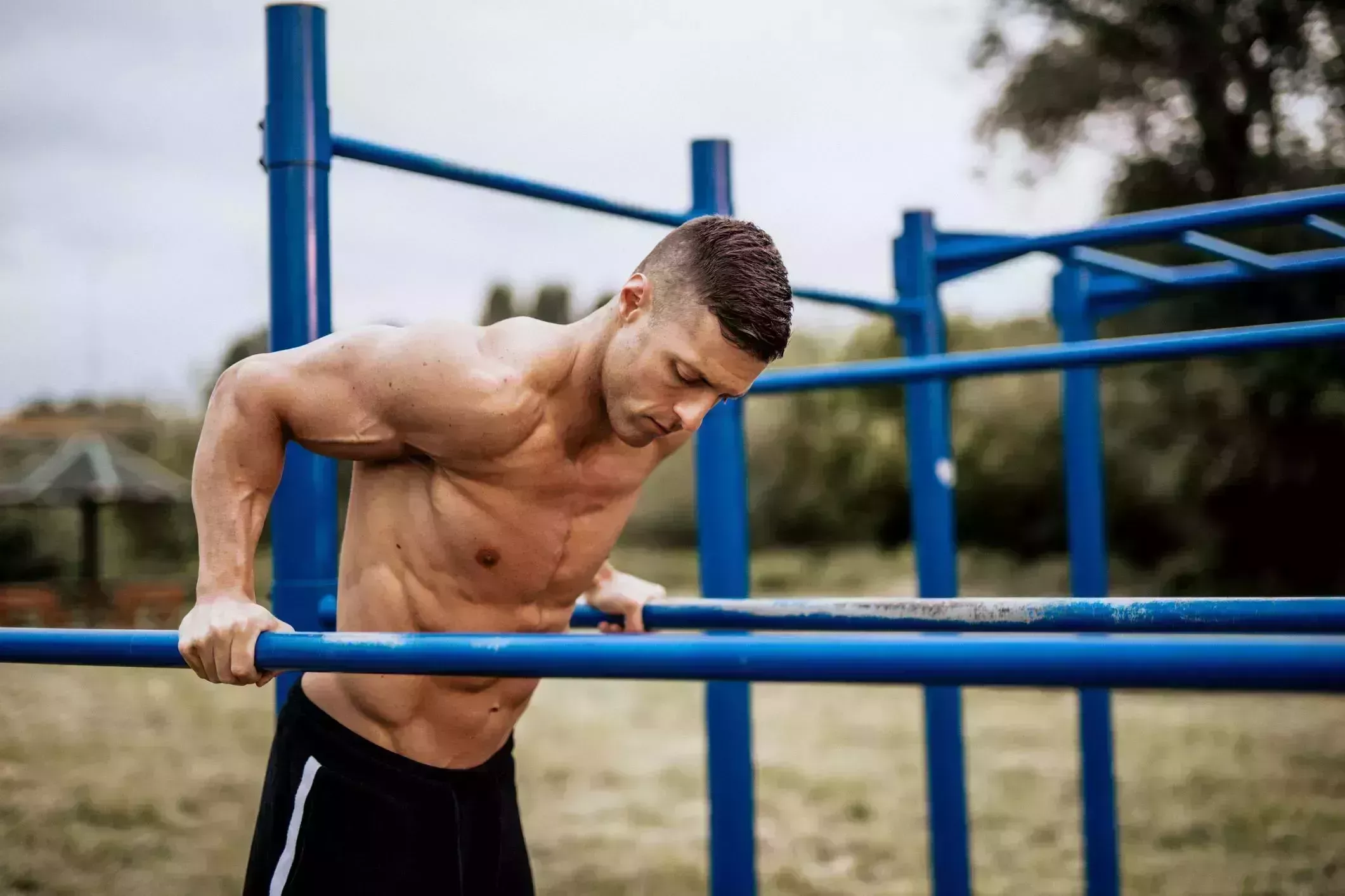 man motivating friend doing squats, lifting kettlebells in gym