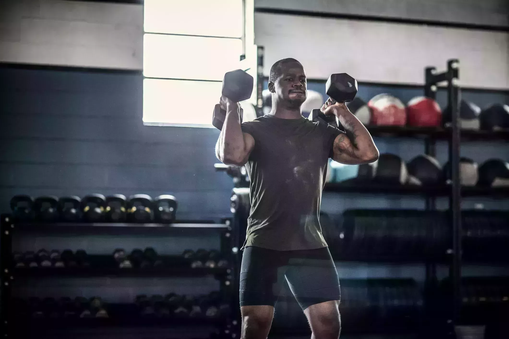 man lifting dumbells at cross training gym