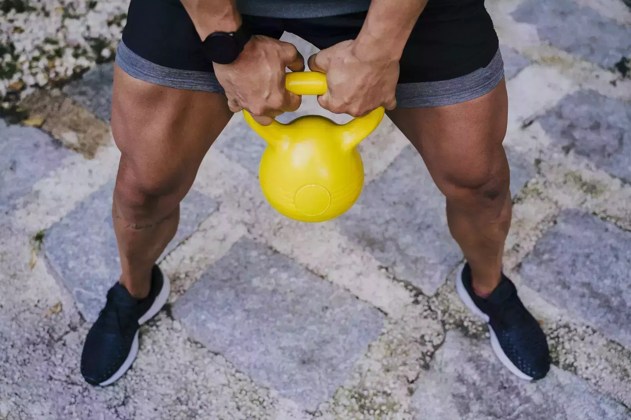 mid adult man lifting kettlebell while standing in yard