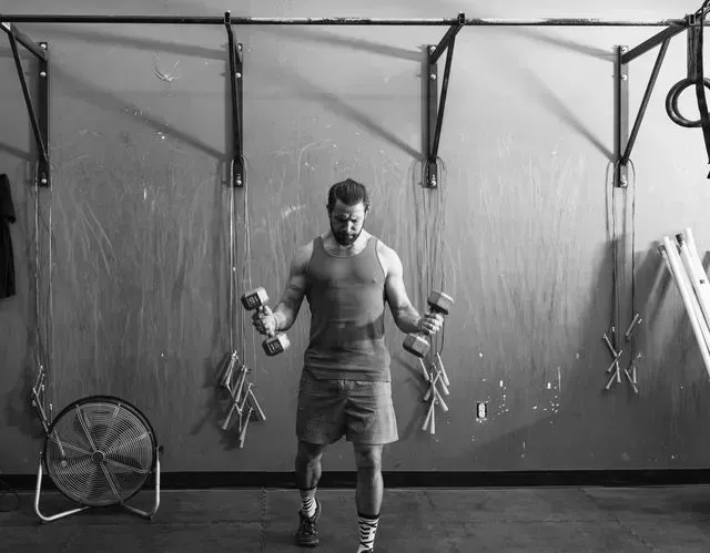 mixed race man lifting dumbbells in gymnasium