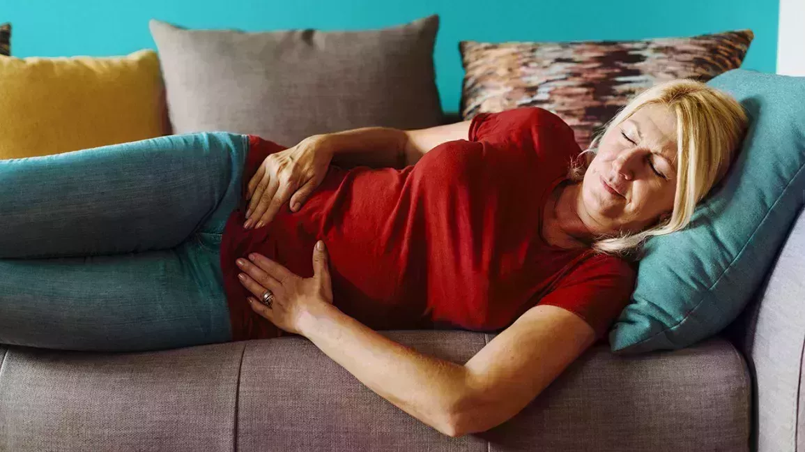 mature adult female lying on sofa experiencing pelvic pain