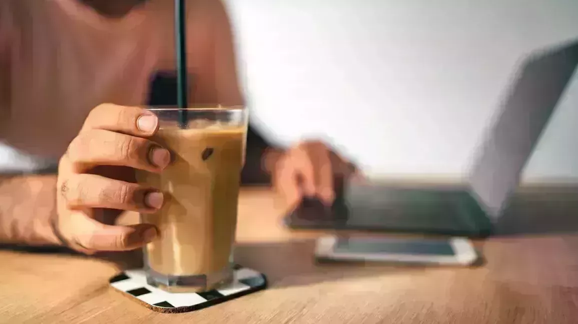 Someone reaching for their iced coffee as they research asthma and cold drinks. 