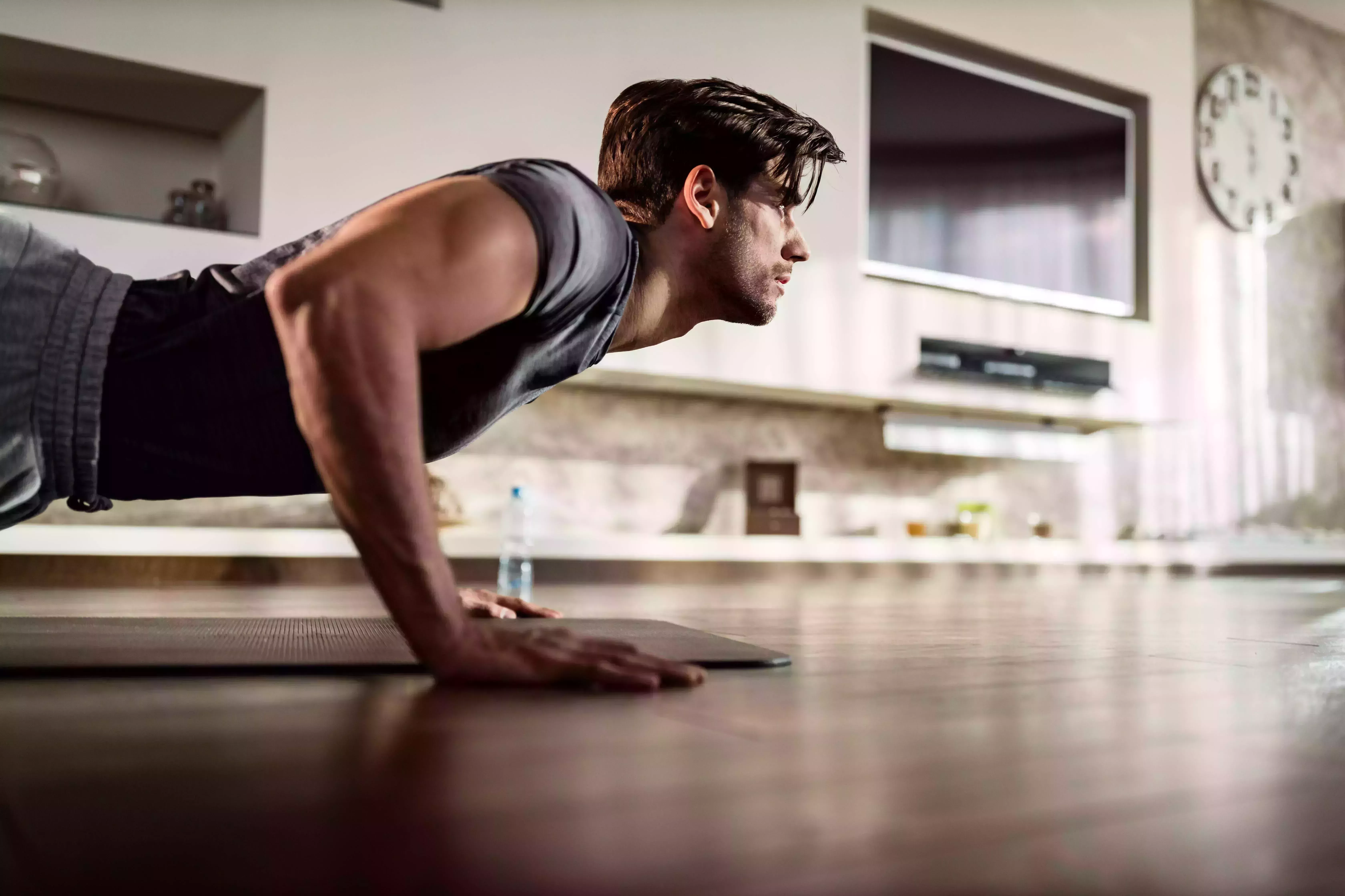 determined athletic man exercising push ups on a floor in the living room copy space