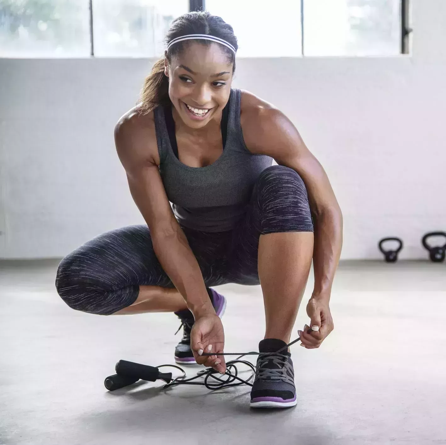 smiling female athlete tying shoelace in gym