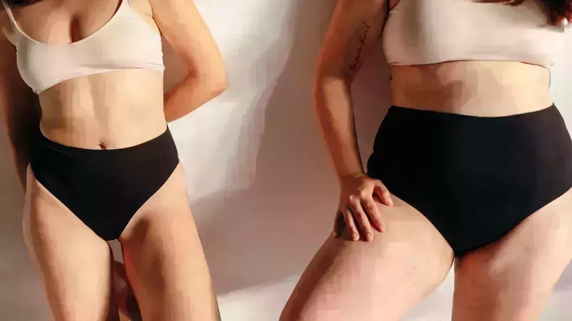 two people in their bra and underwear leaned against a wall chatting