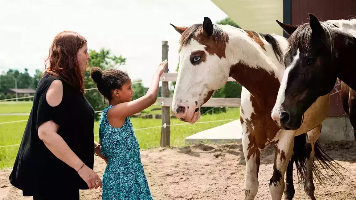 A equine therapist introduces her client to some of the horses. 