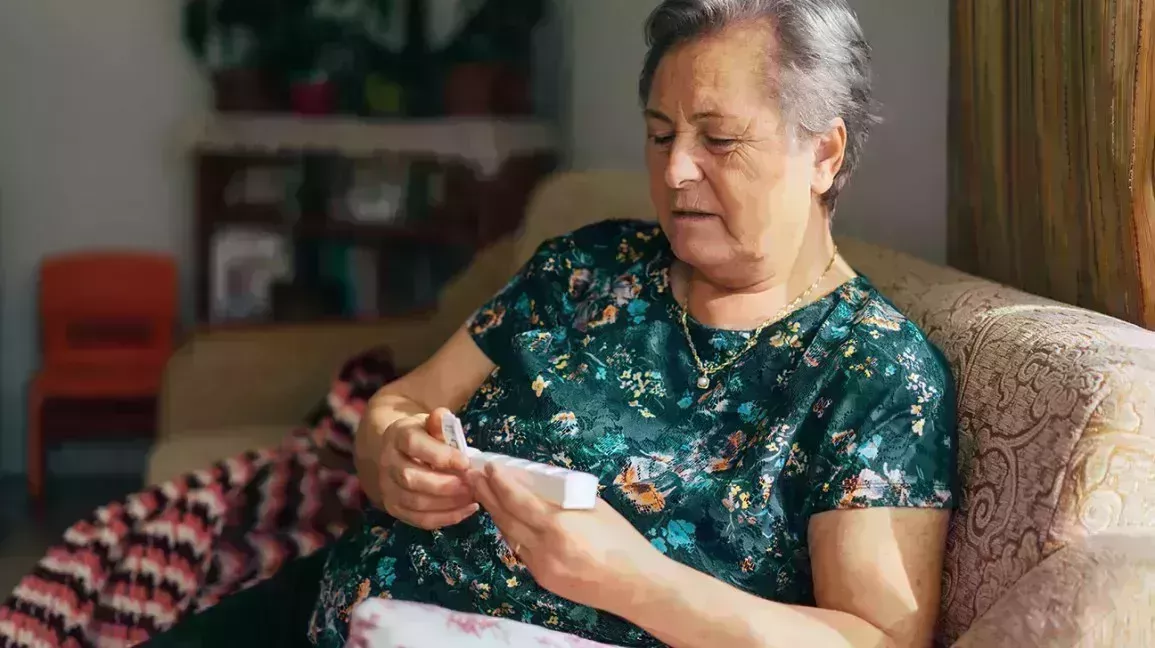 older woman reviewing the medications in her weekly pill organizer
