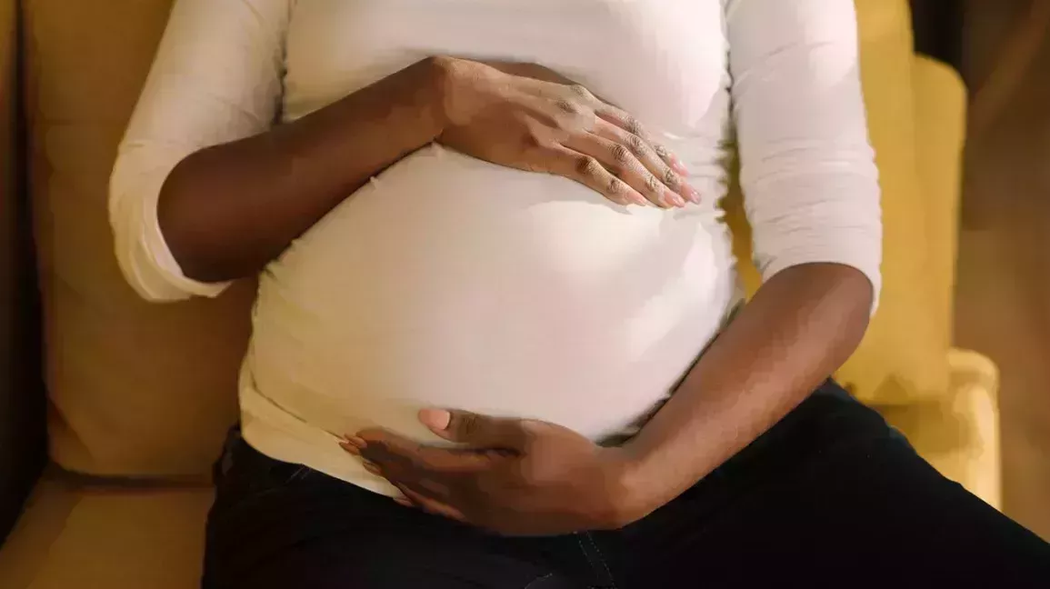 woman with anemia in her third trimester of pregnancy holding her pregnant abdomen