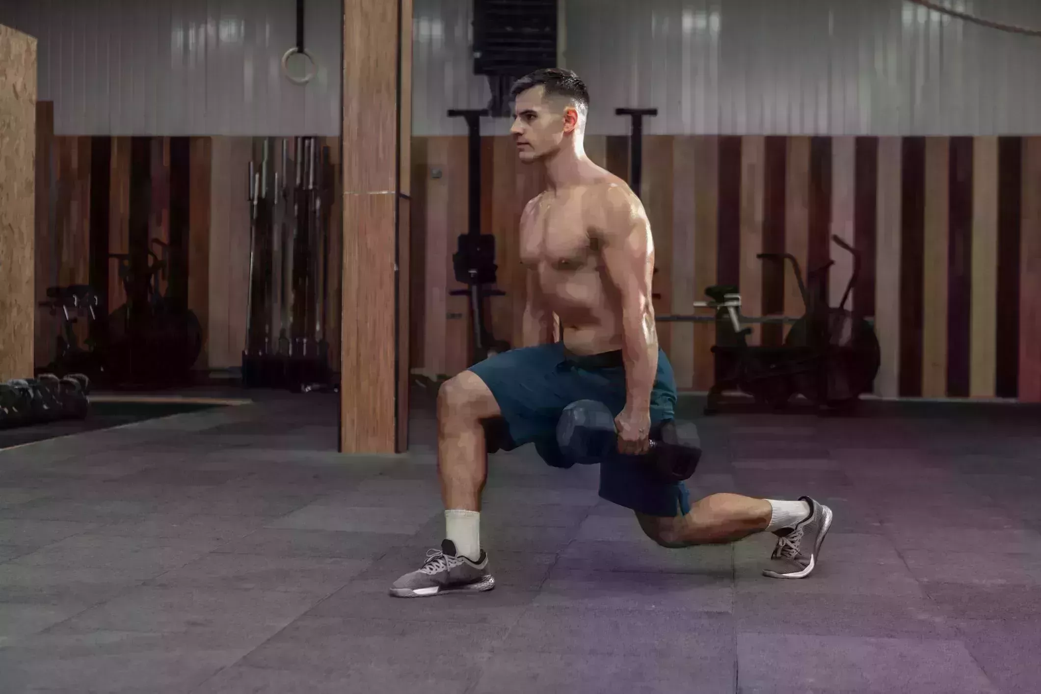 muscular man training his legs, doing lunges with heavy dumbbells in modern gym healthy lifestyle concept