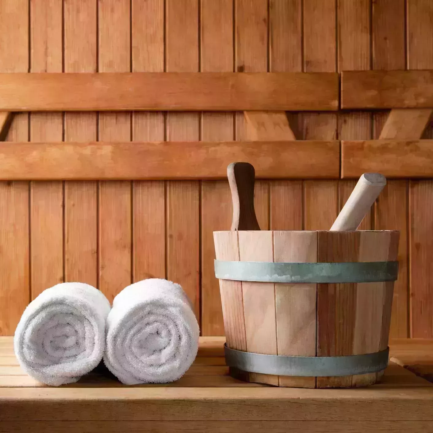 wooden bucket and white rolled towels in a sauna