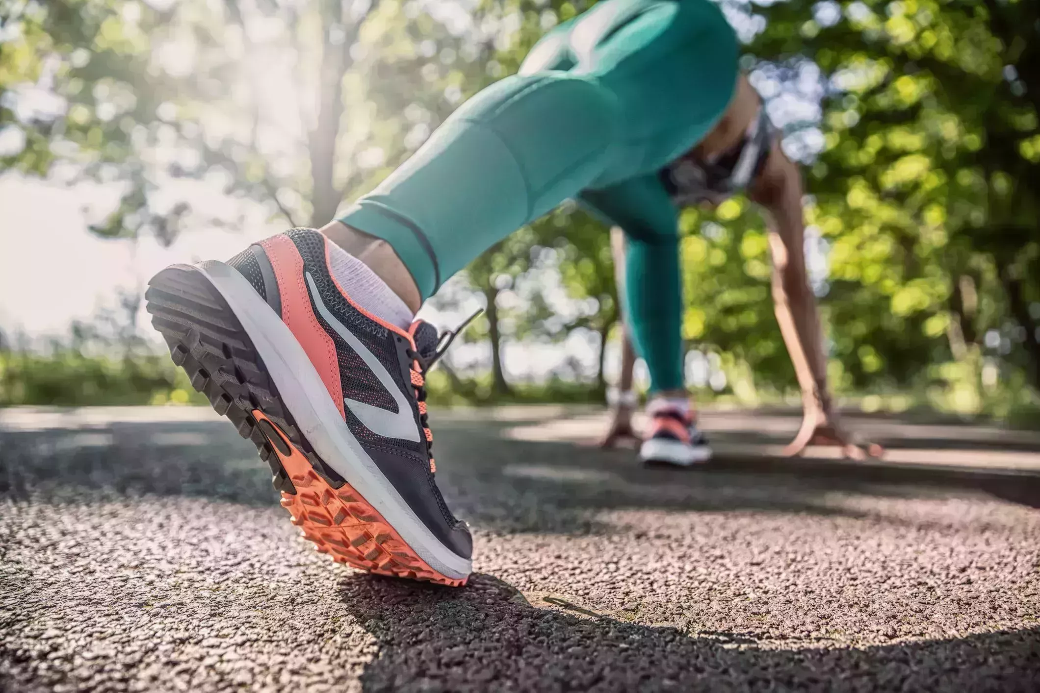 morning stretches – Detail of a female runner shoe as she gets ready for a sprinter start of a run. morning stretches – woman in workout clothes doing a runners lunge and shot from perspective of her outstretched leg