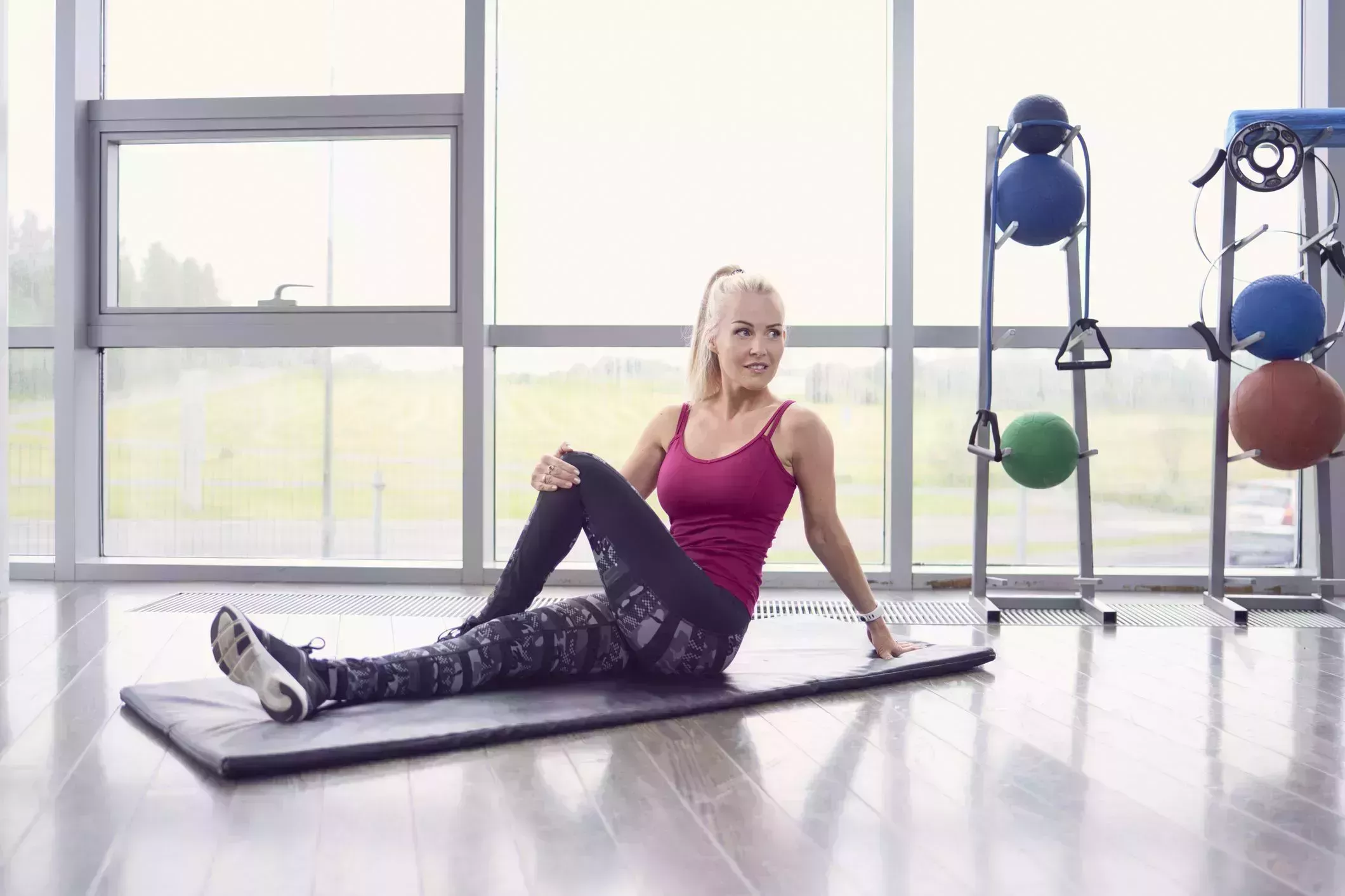morning stretches – Female athlete exercising on mat morning stretches – woman on an exercise mat in a gym doing a seated twist stretch