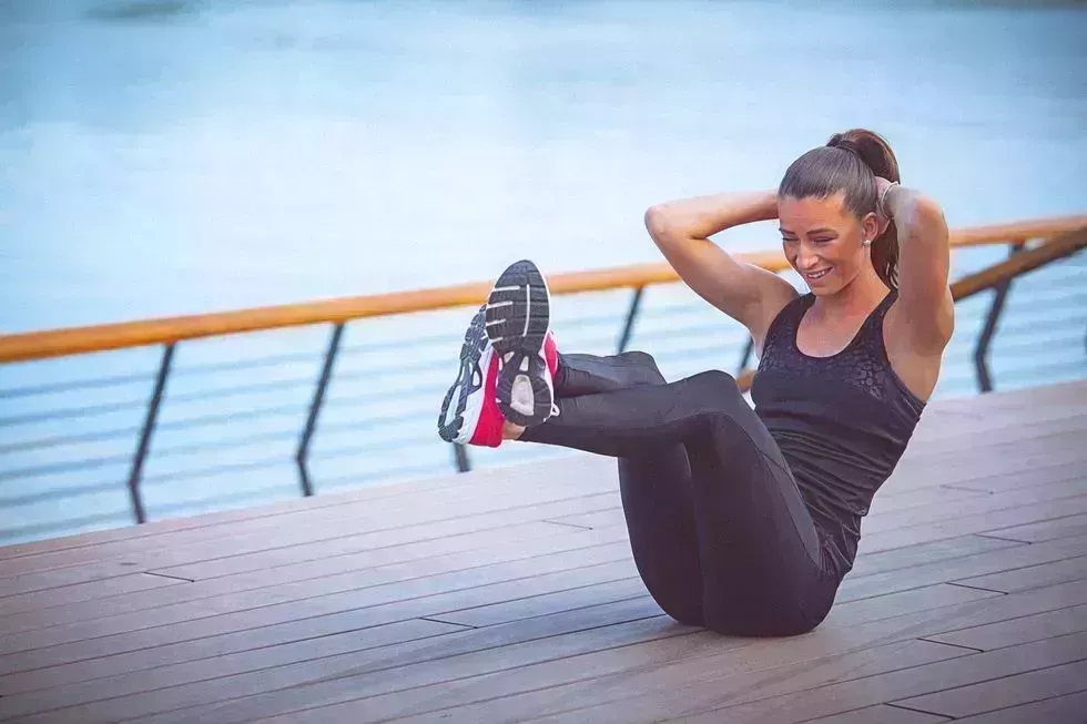 young female athlete performs ab crunches outdoors