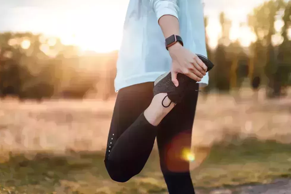 Young Woman Stretching Legs In The Park After Exercise young woman stretching legs in the park after exercise