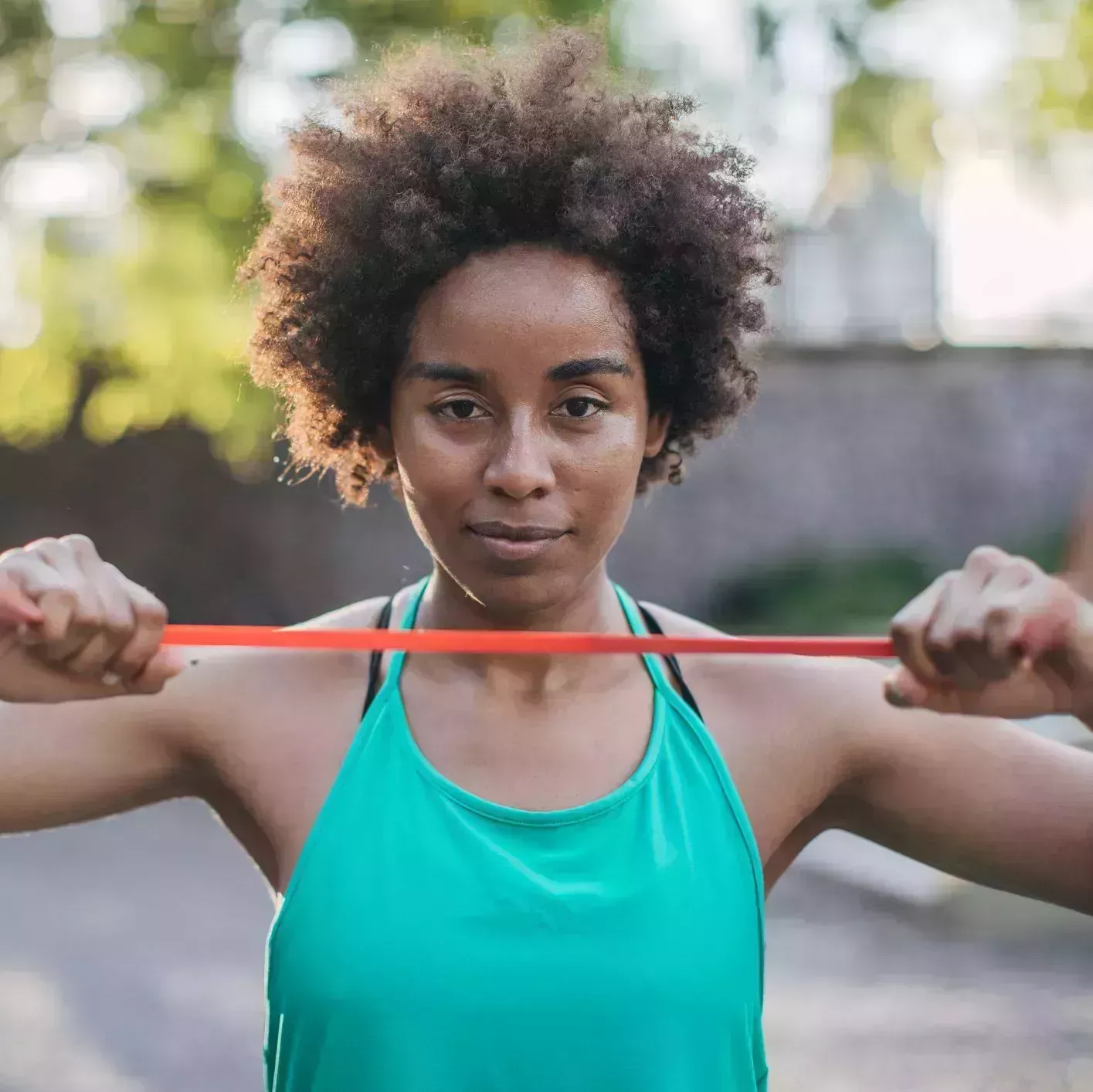 beautiful young black woman exercising in park with a resistance band