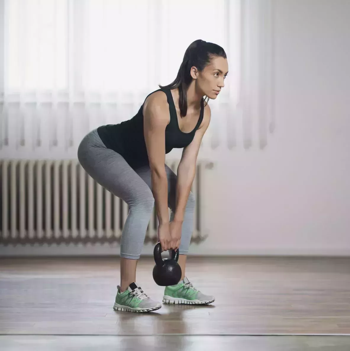 woman in workout clothes doing a deadlift exercise movement