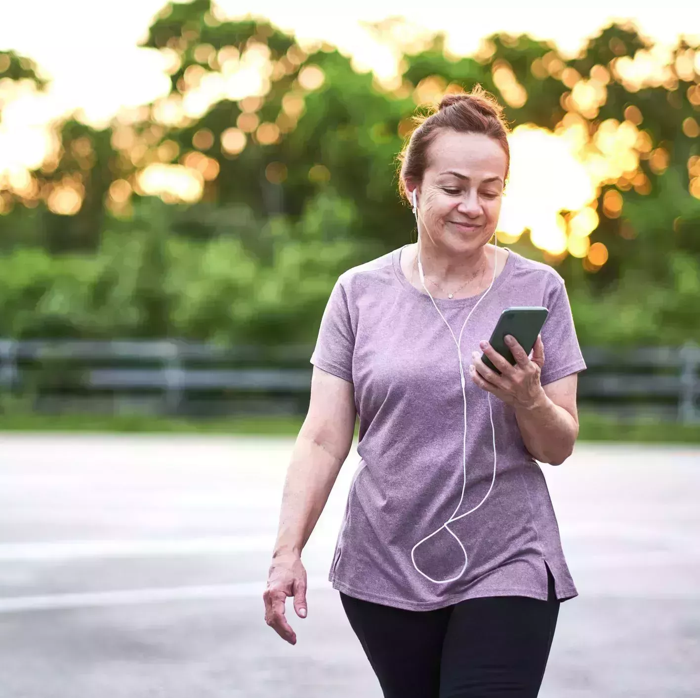 mature woman walking at sunset carrying a mobile phone