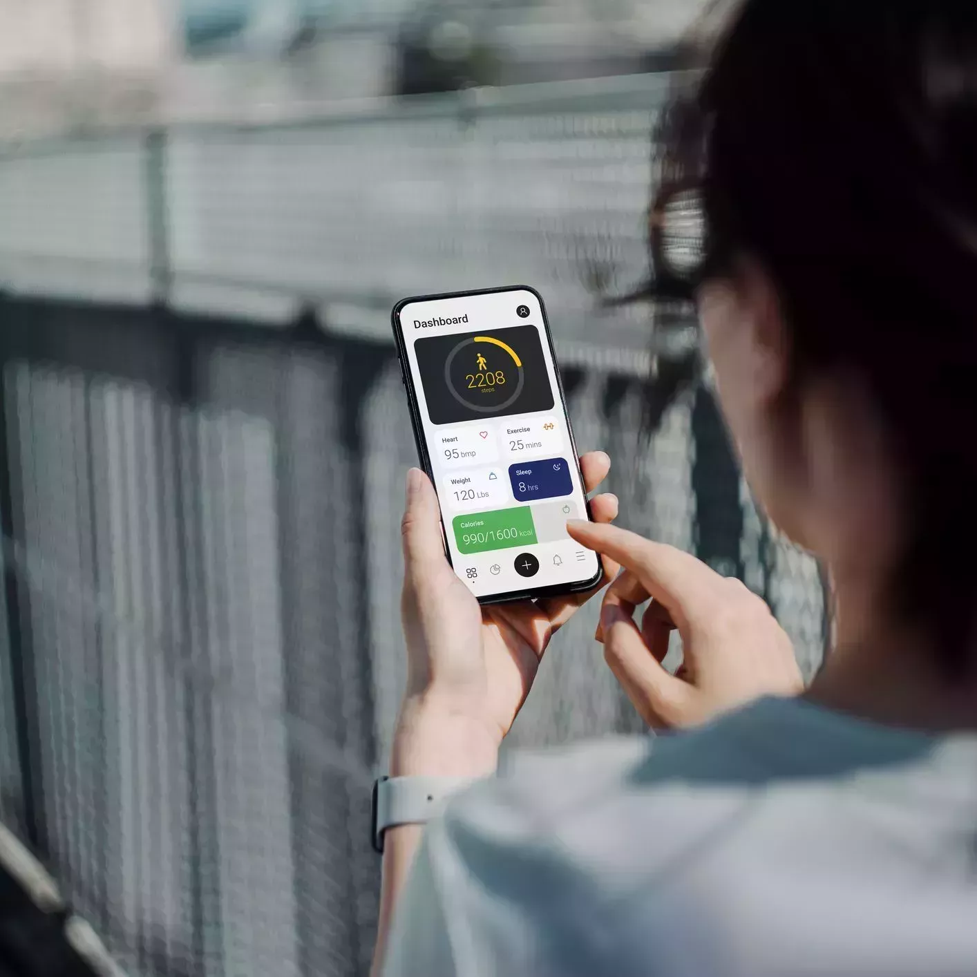 over the shoulder view of young asian sports woman using fitness app on smartphone to monitor her training progress while doing outdoor walk exercising in the fresh bright morning with shades of sunlight